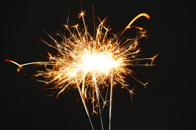 Photo of Bright burning sparklers on black background, closeup