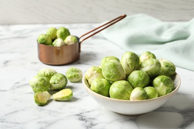 Photo of Bowl with fresh Brussels sprouts on marble table. Space for text