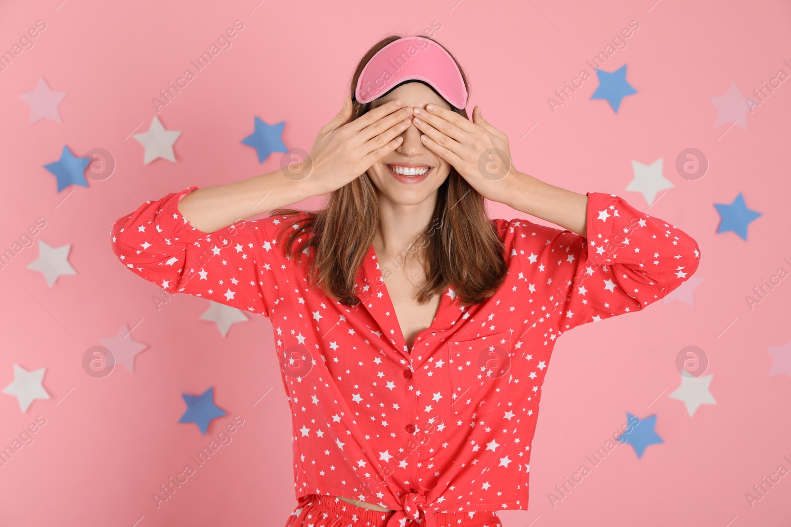 Photo of Beautiful woman wearing pajamas and sleep mask on pink background. Bedtime