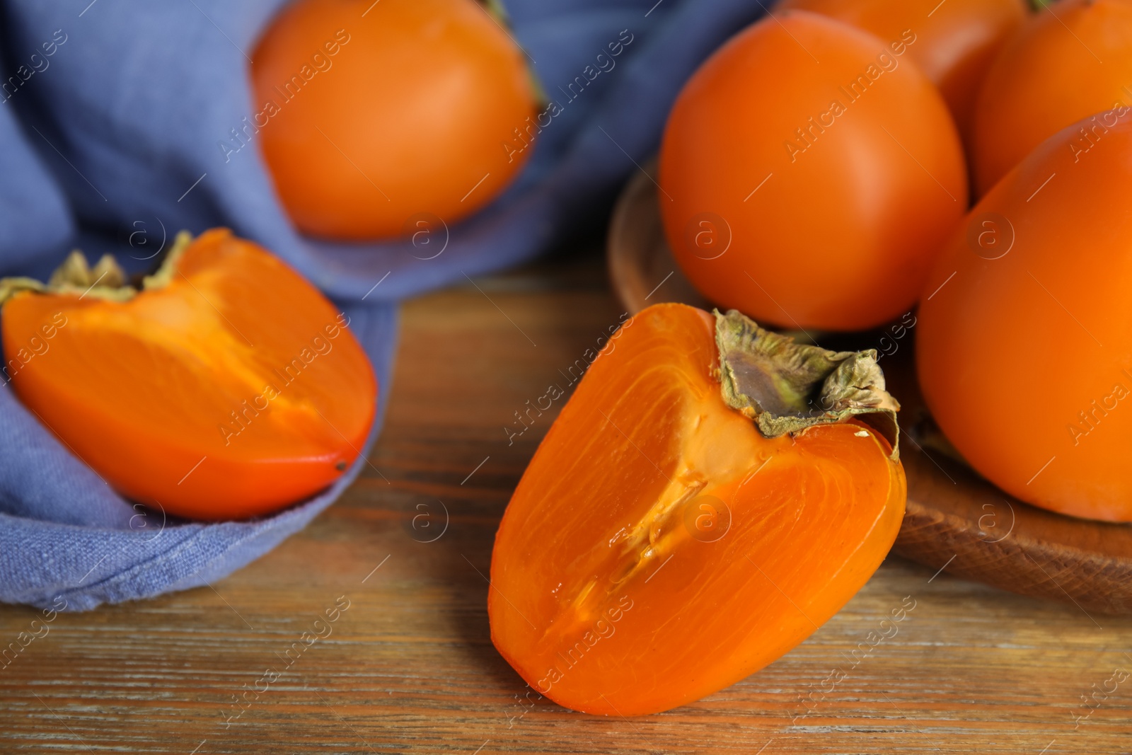 Photo of Tasty ripe persimmons on wooden table, closeup