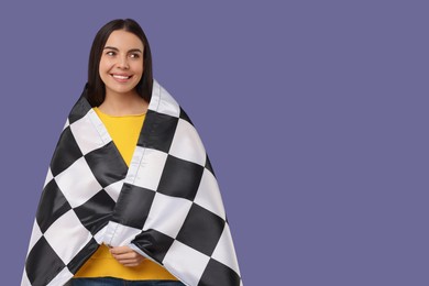 Photo of Happy young woman with checkered flag on violet background, space for text