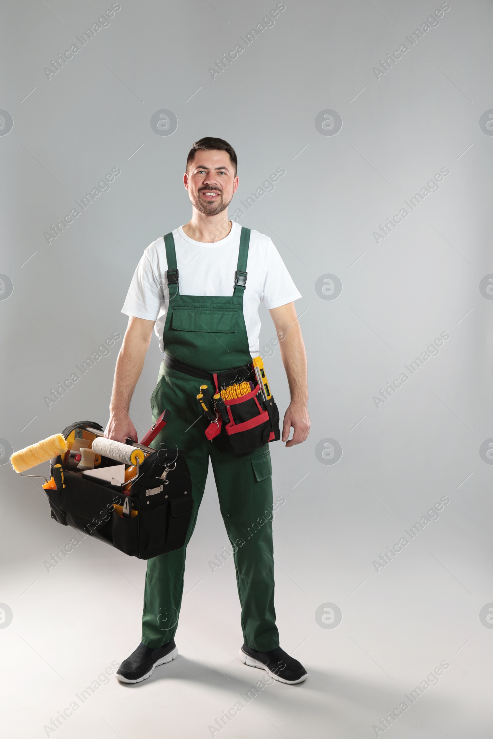 Photo of Full length portrait of professional construction worker with tools on grey background