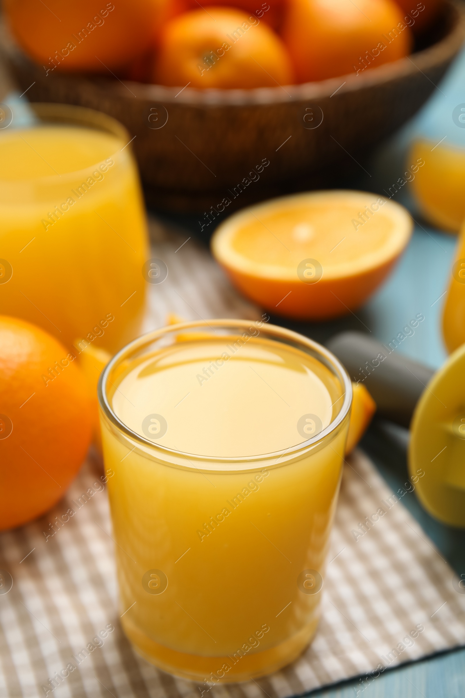 Photo of Freshly made juice, oranges and reamer on blue table