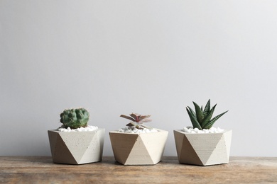 Beautiful succulent plants in stylish flowerpots on table against light background, space for text. Home decor