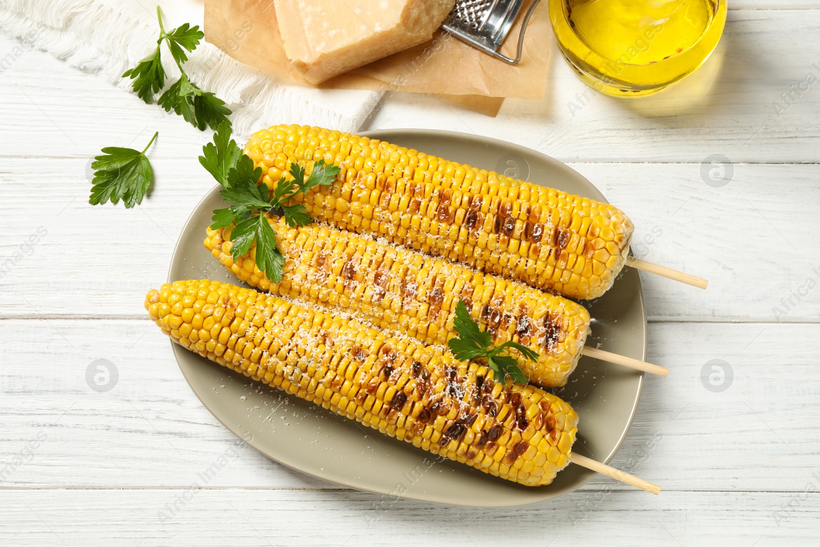 Photo of Tasty grilled corn on white wooden table, flat lay