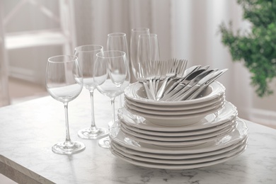 Photo of Set of clean dishware, cutlery and wineglasses on table indoors