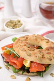 Tasty bagel with salmon and tomatoes on table, closeup