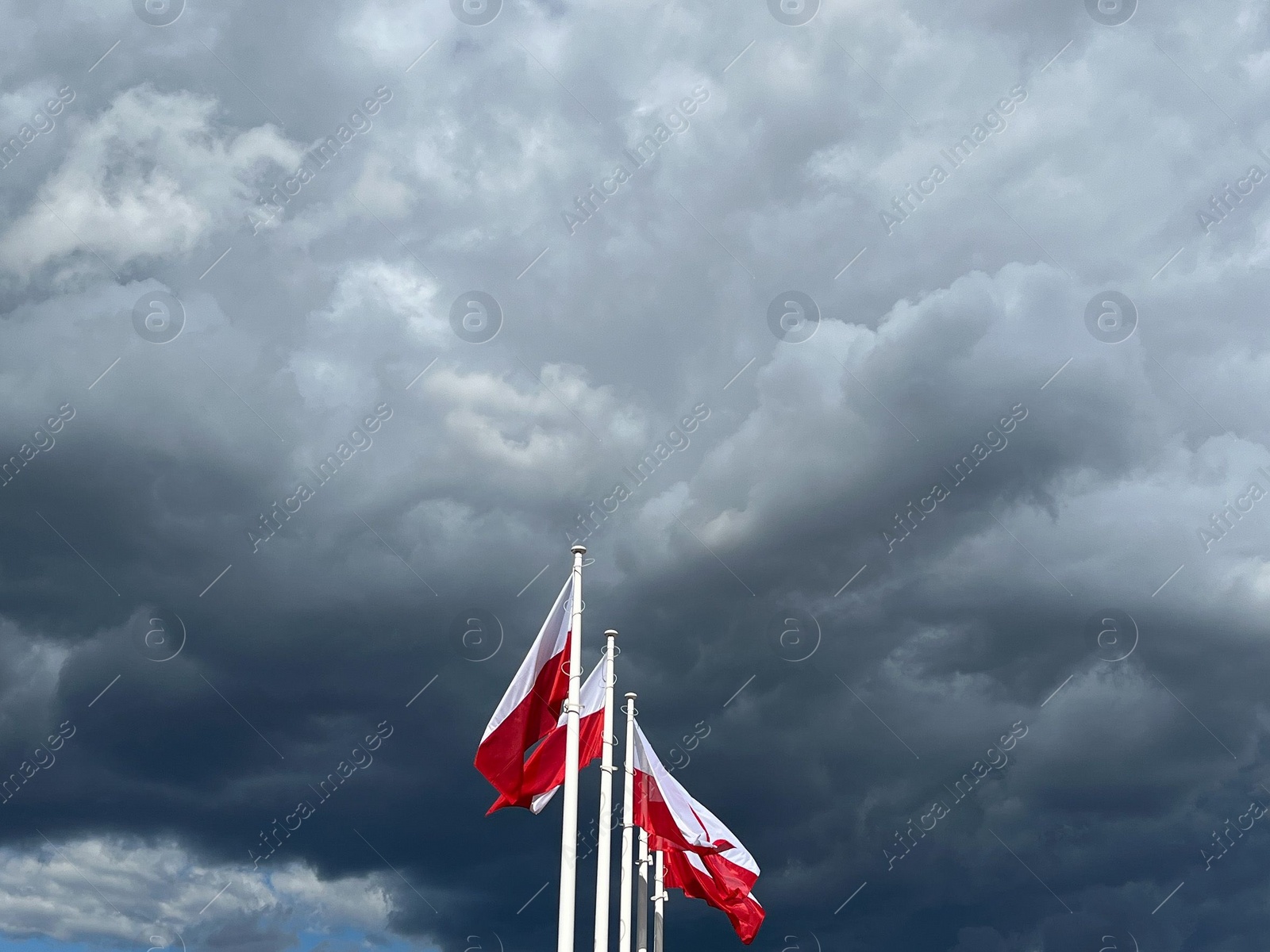 Photo of WARSAW, POLAND - JULY 17, 2022: Flags of Poland fluttering against beautiful sky with clouds