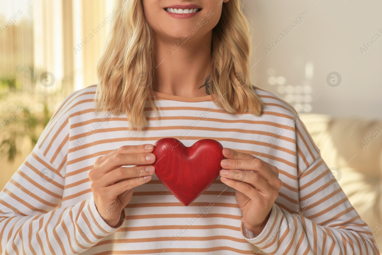 Photo of Happy volunteer holding red heart with hands indoors, closeup