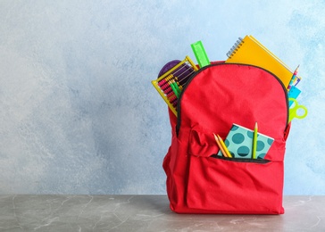 Photo of Backpack with different colorful stationery on table. Back to school