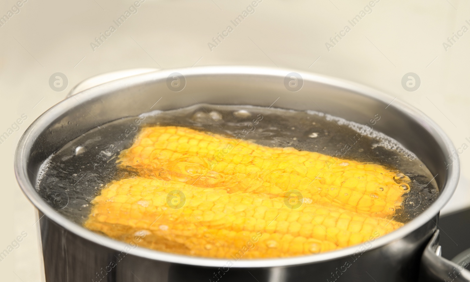 Photo of Pot with boiling corn in kitchen, closeup