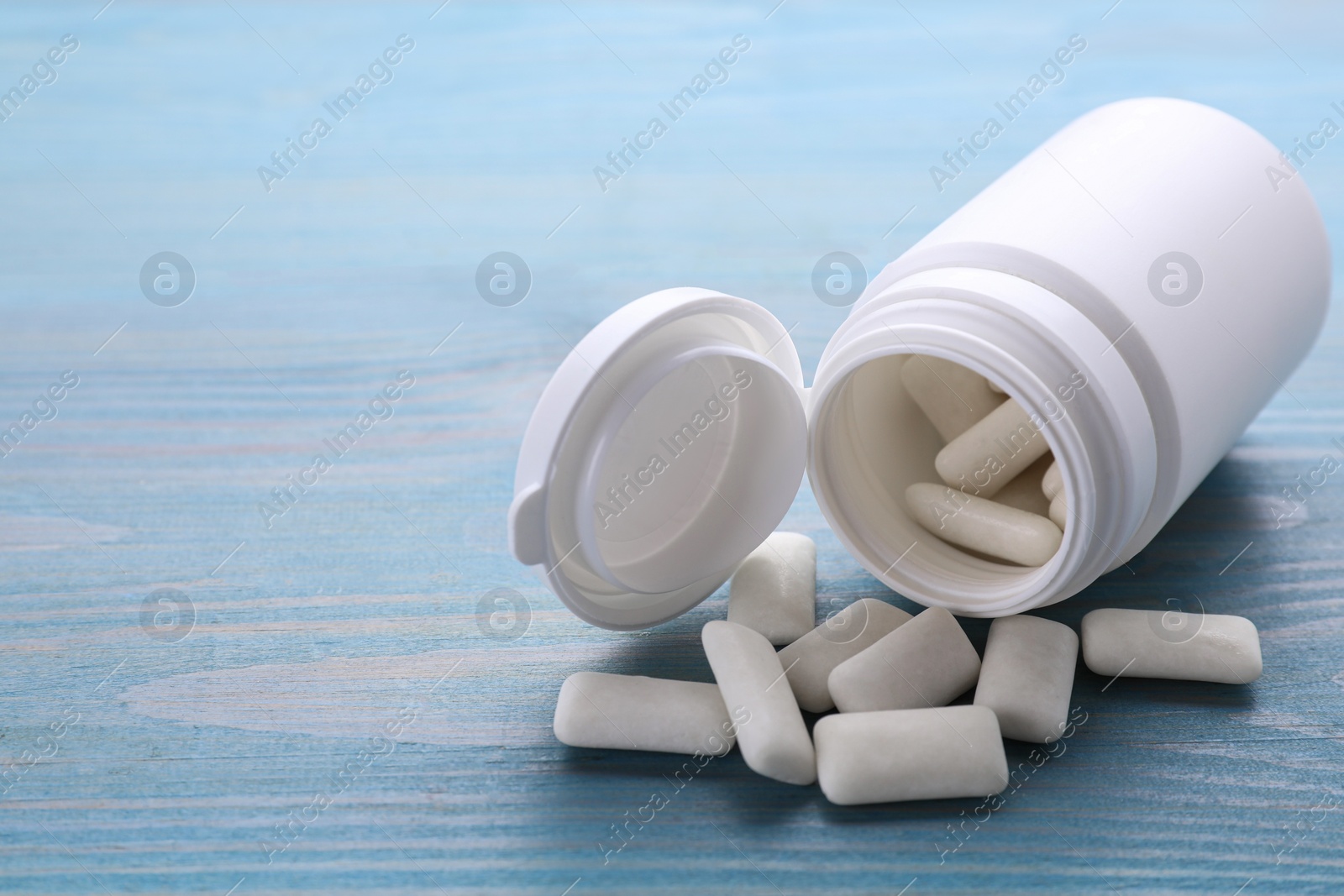 Photo of Jar with chewing gums on light blue wooden table