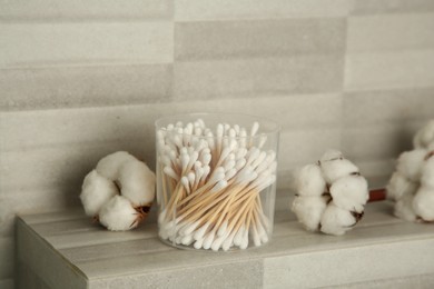 Photo of Cotton swabs and flowers on tiled surface indoors