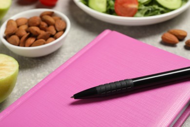 Weight loss concept. Notebook with pen and different products on grey table, closeup