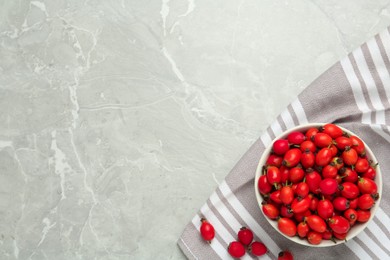 Ceramic bowl with rose hip berries on grey table, top view and space for text. Cooking utensil