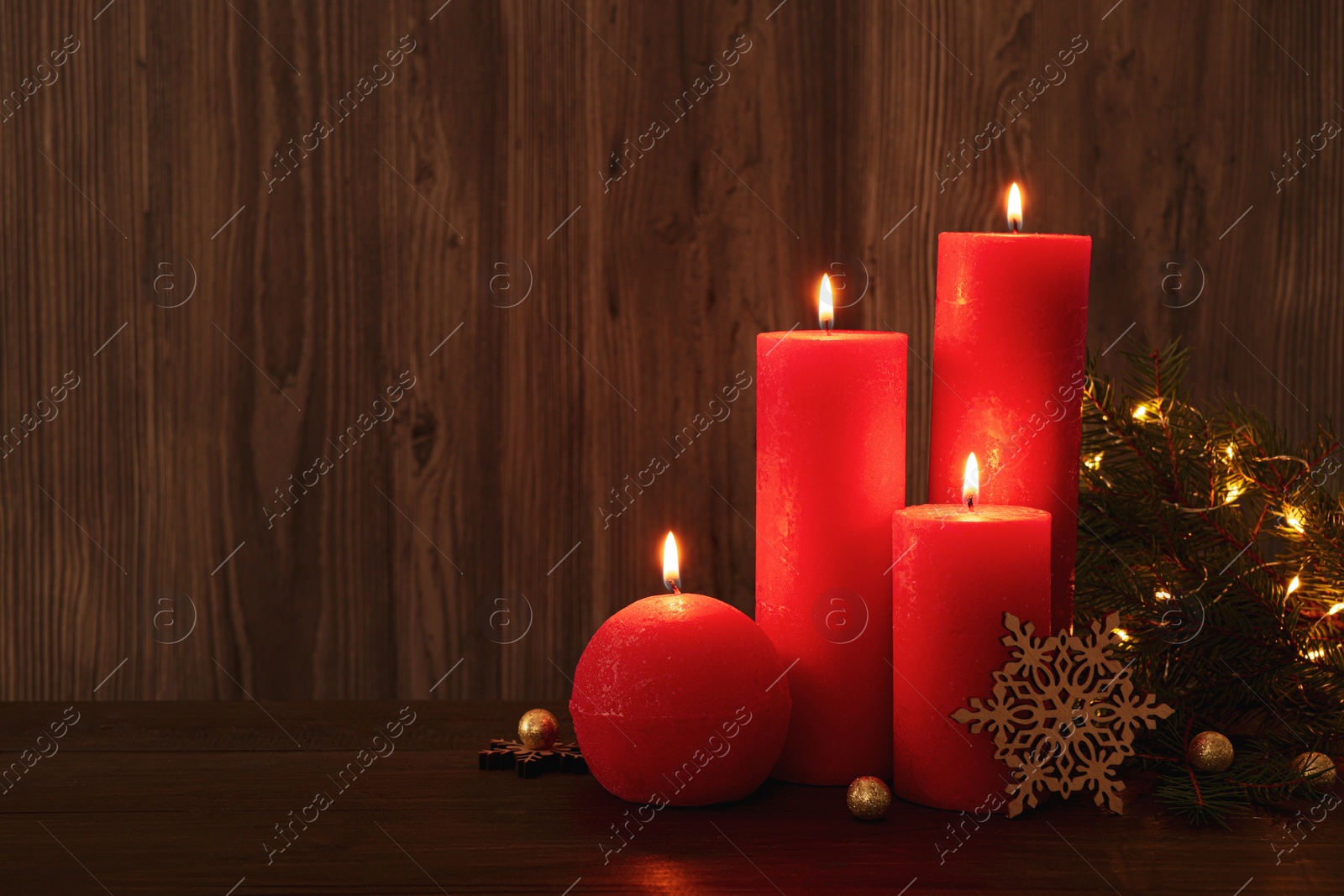 Photo of Beautiful burning candles with Christmas decor on wooden table, space for text