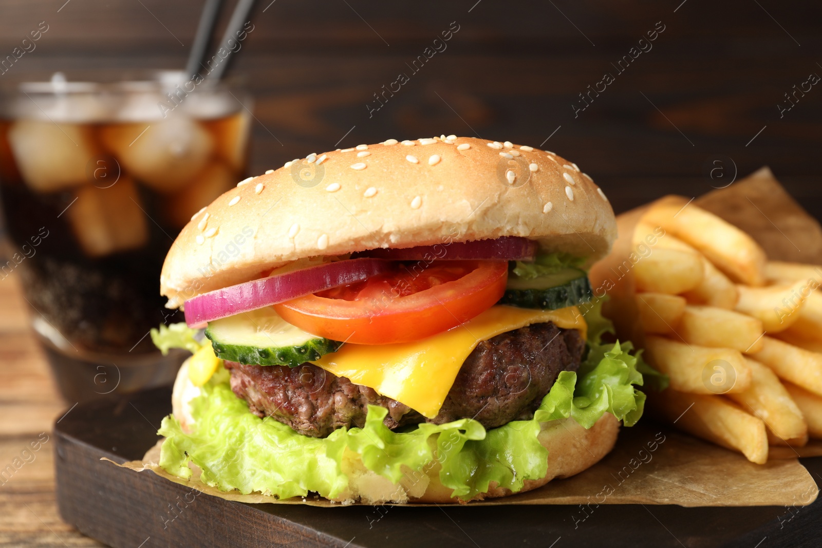 Photo of Delicious burger, soda drink and french fries served on wooden table, closeup