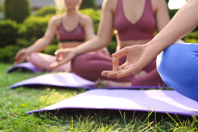 Women meditating on yoga mats outdoors, closeup