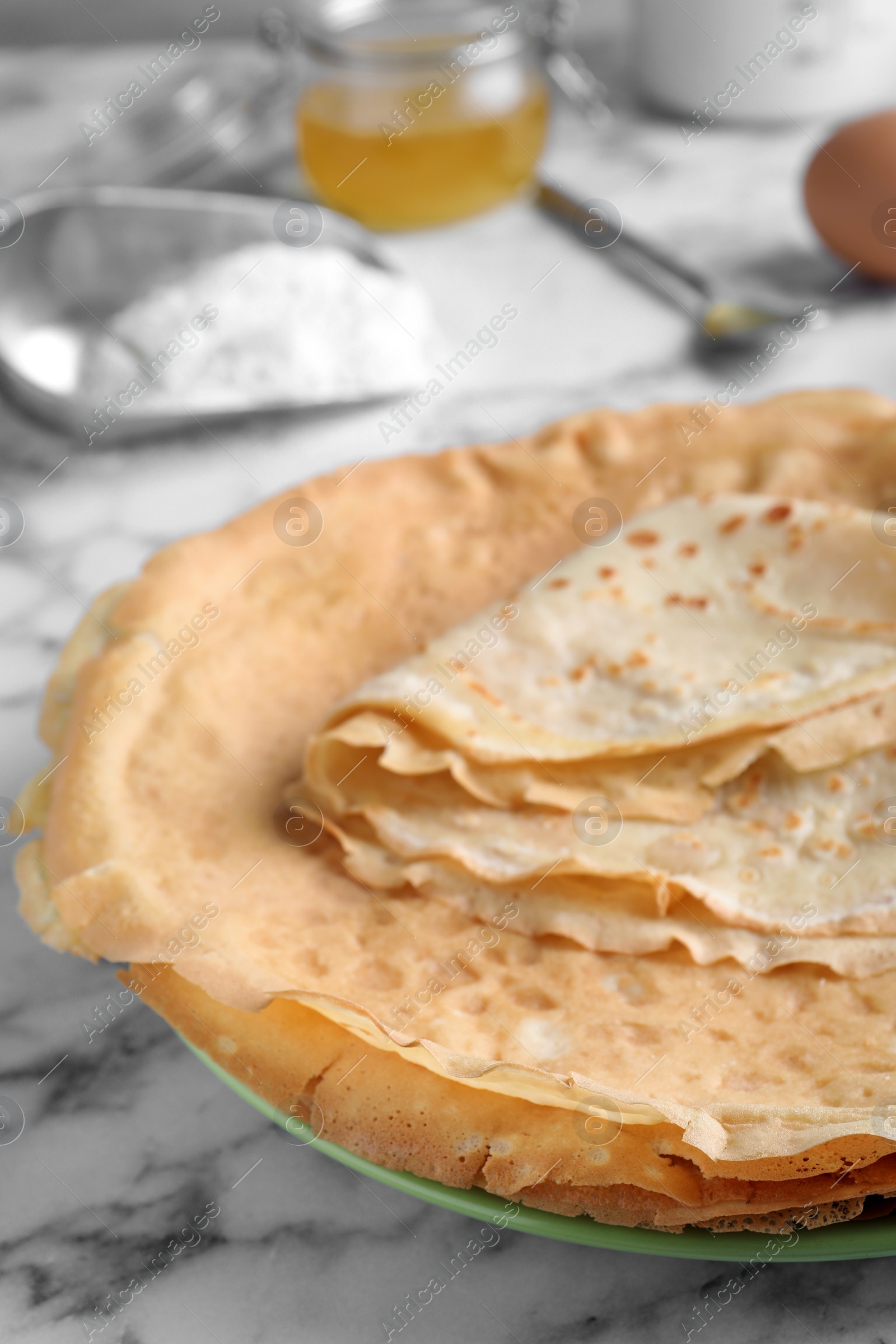 Photo of Delicious crepes on white marble table, closeup