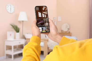 Image of Man using smart home security system on mobile phone indoors, closeup. Device showing different rooms through cameras