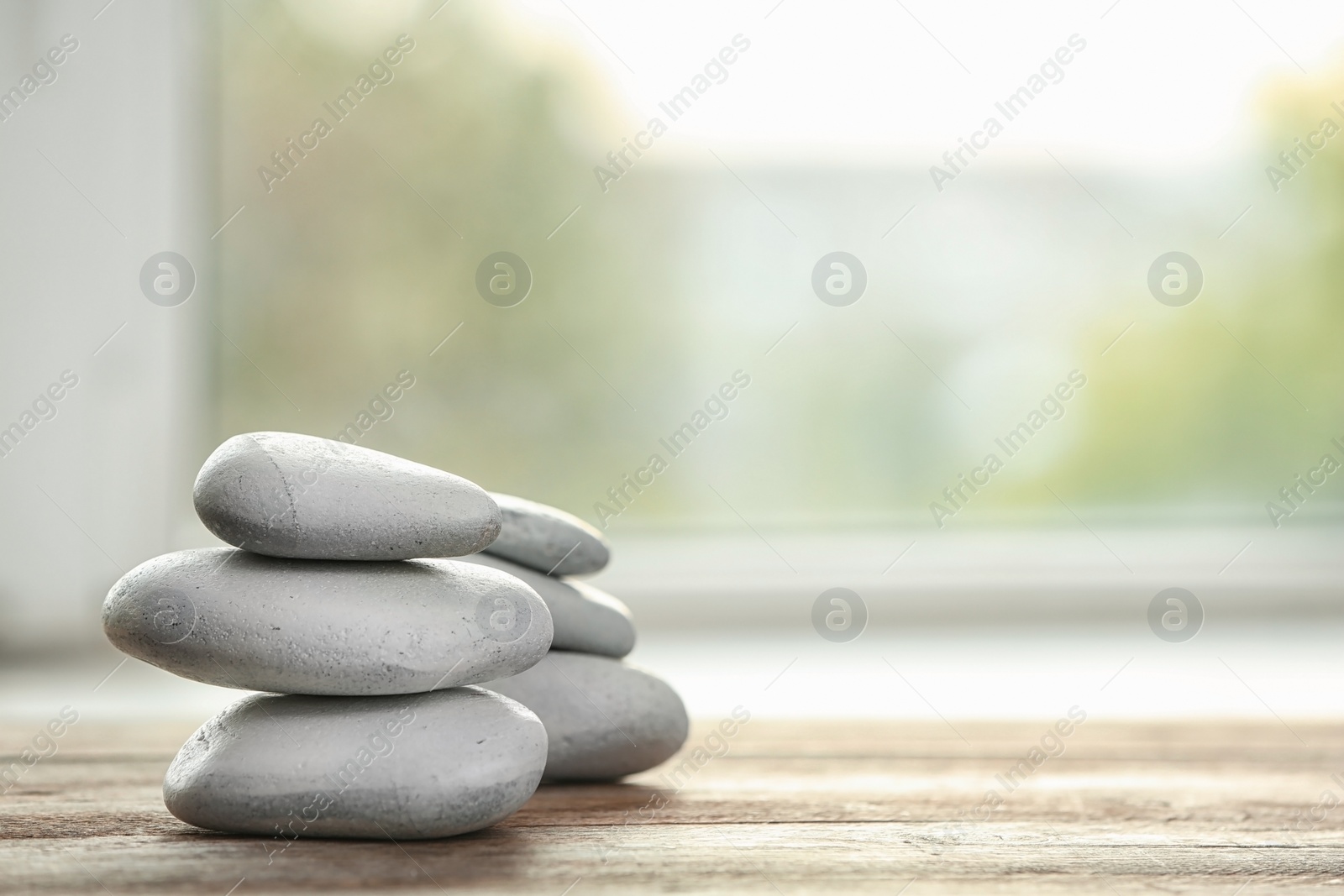 Photo of Spa stones on table against blurred background. Space for text