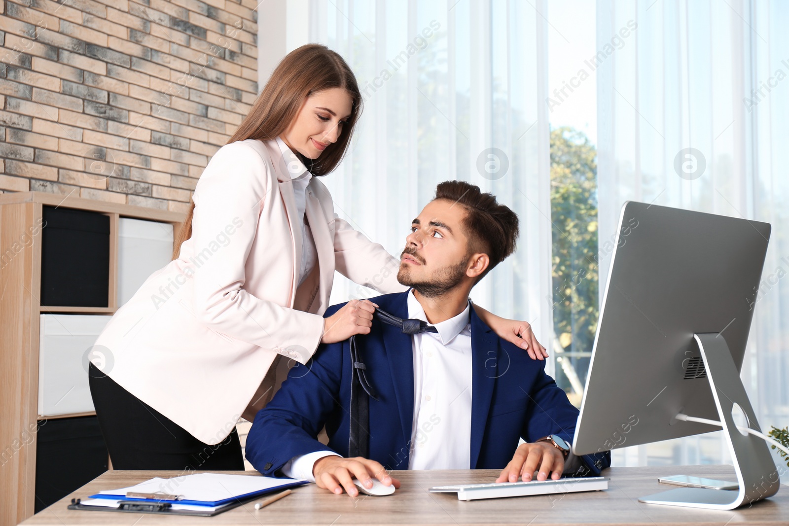 Photo of Woman molesting her male colleague in office. Sexual harassment at work