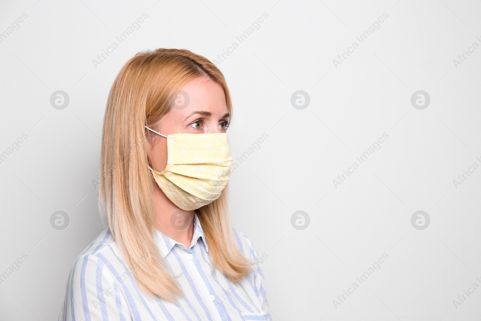 Photo of Woman wearing handmade cloth mask on white background, space for text. Personal protective equipment during COVID-19 pandemic