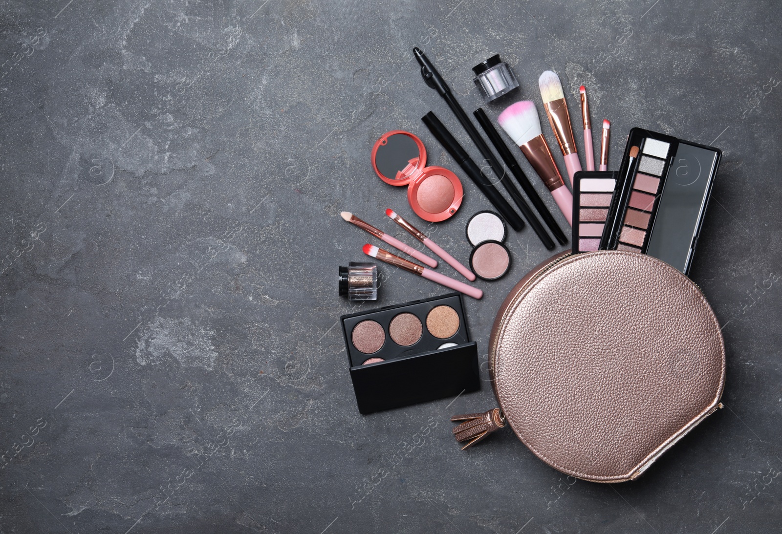 Photo of Cosmetic bag with makeup products and beauty accessories on grey stone background, flat lay. Space for text