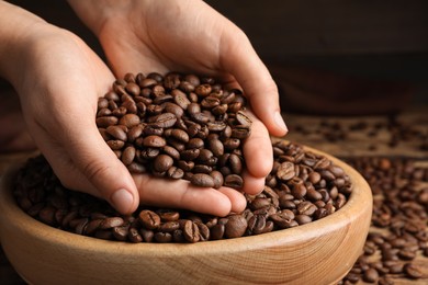 Photo of Woman taking pile of roasted coffee beans from bowl, closeup