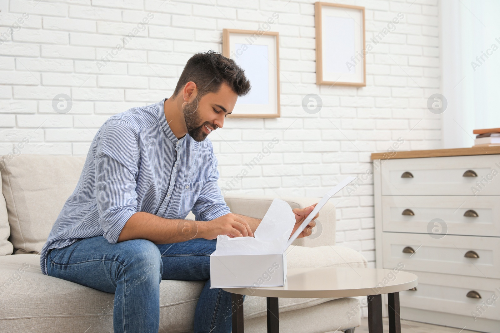 Photo of Man unpacking parcel at home. Online shopping