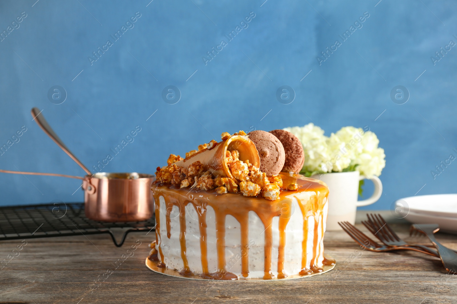 Photo of Delicious homemade cake with caramel sauce and popcorn on table