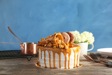 Delicious homemade cake with caramel sauce and popcorn on table