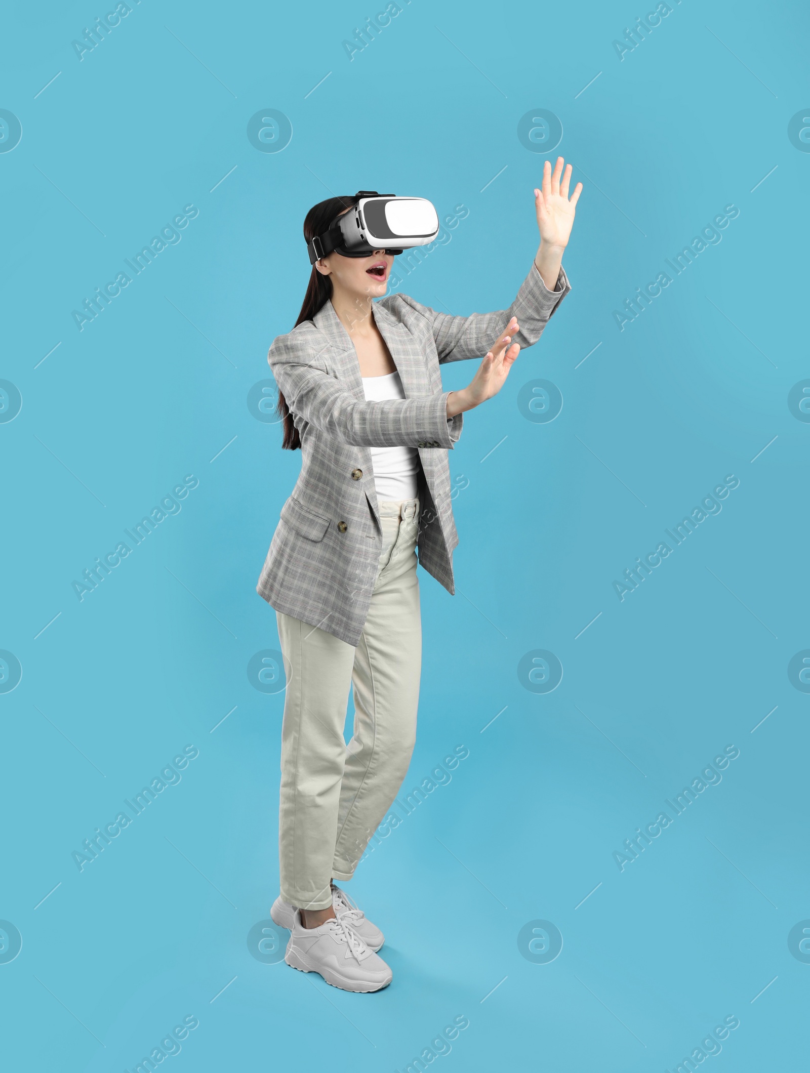 Photo of Woman using virtual reality headset on light blue background