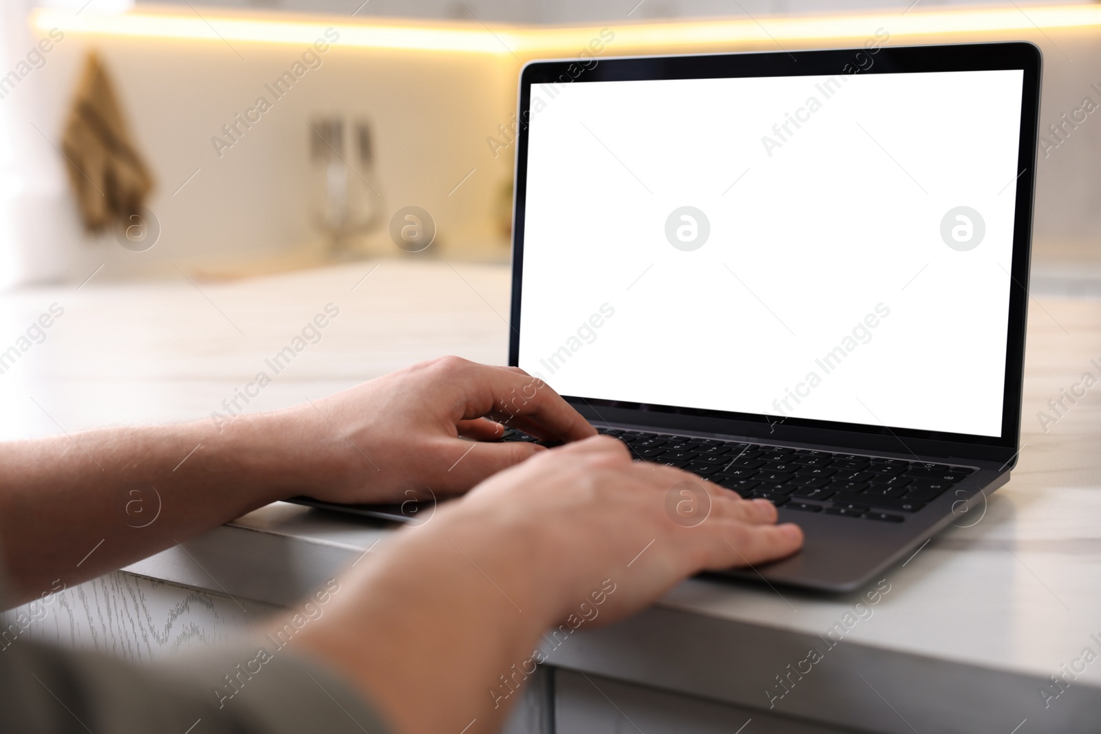 Photo of Man working on laptop at white marble table indoors, closeup
