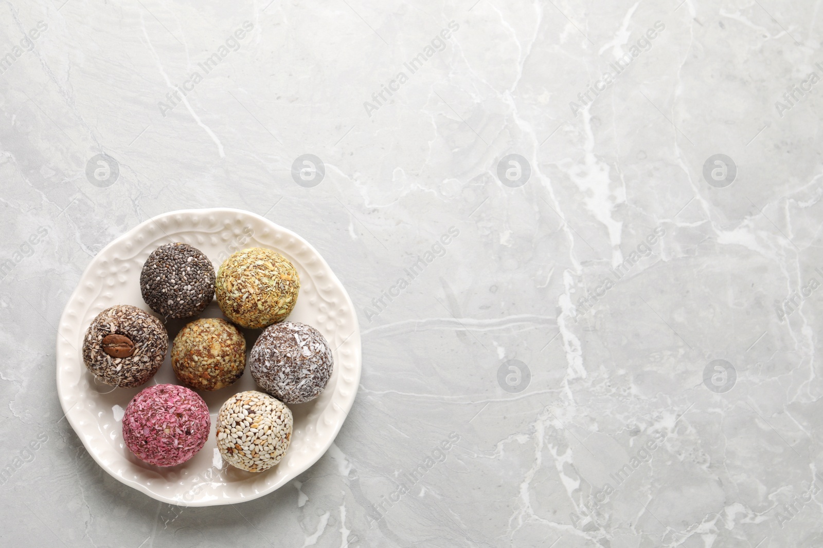 Photo of Delicious vegan candy balls on light grey marble table, top view. Space for text