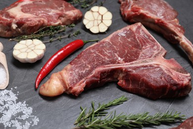 Photo of Fresh raw beef cuts and different spices on light grey textured table, closeup