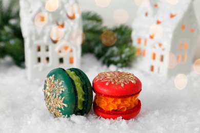 Different decorated Christmas macarons on table with artificial snow, closeup