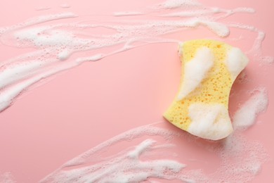 Yellow sponge with foam on pink background, top view. Space for text