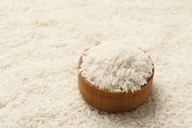 Photo of Bowl on raw basmati rice, closeup. Space for text