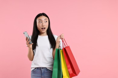 Photo of Surprised woman with shopping bags on pink background. Space for text