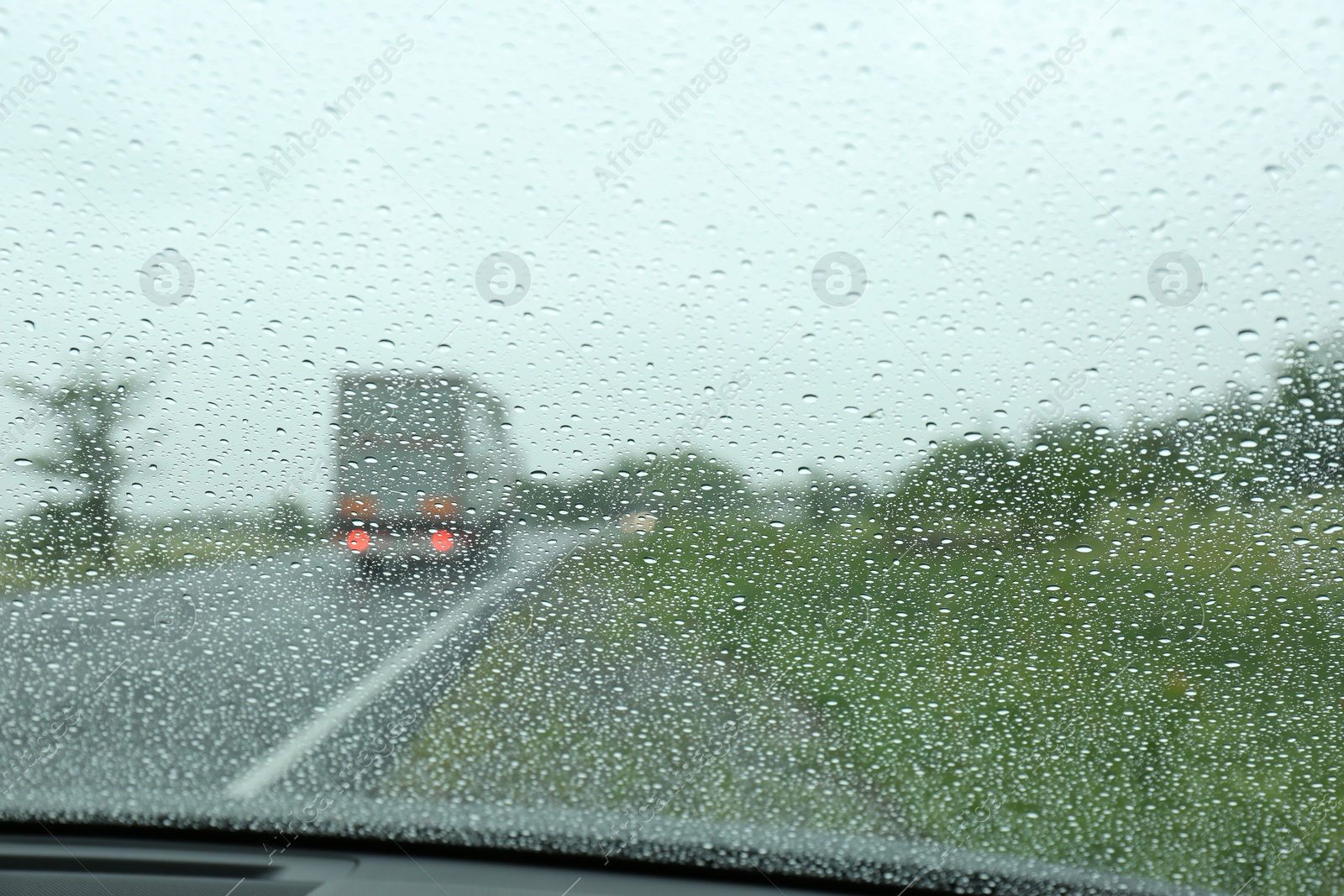 Photo of Blurred view of country road through wet car window. Rainy weather