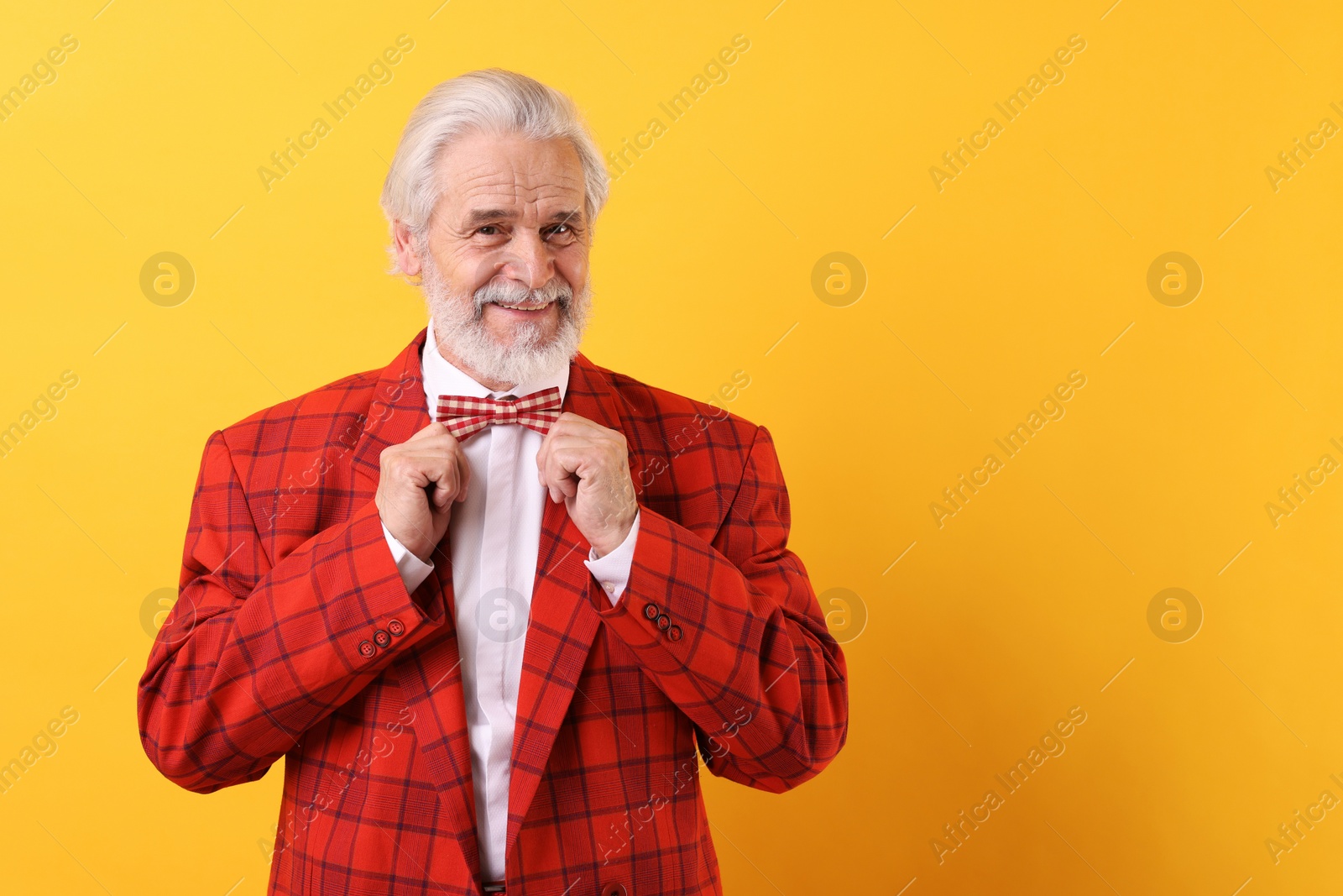 Photo of Portrait of grandpa with stylish red suit and bowtie on yellow background, space for text