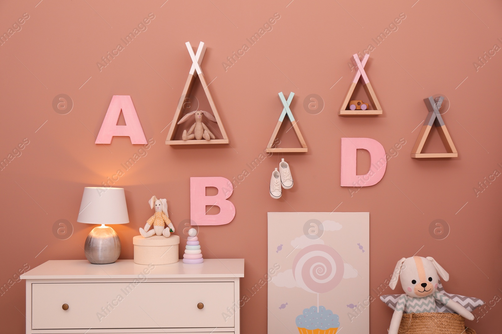 Photo of Cabinet, toys and teepee shaped shelves near beige wall. interior design