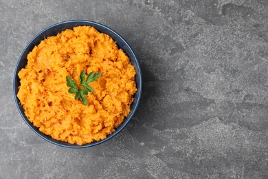 Photo of Bowl with mashed sweet potatoes on grey background, top view. Space for text