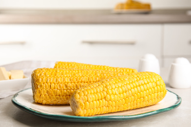 Photo of Delicious boiled corn on table in kitchen