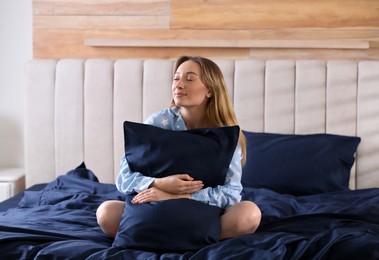 Photo of Young woman hugging pillow on comfortable bed with silky linens