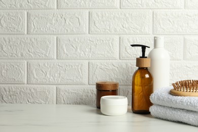 Different bath accessories and personal care products on white table near brick wall, space for text