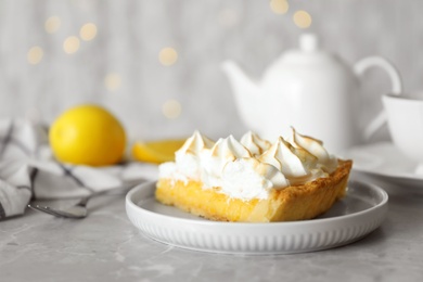 Photo of Plate with piece of delicious lemon meringue pie on light grey table