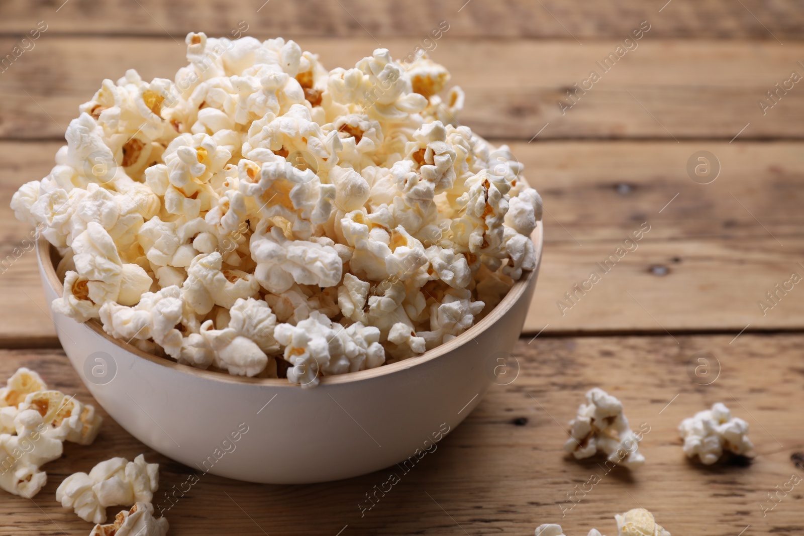 Photo of Tasty popcorn on wooden table, closeup view