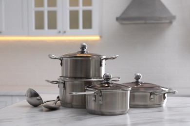 Photo of Set of new clean cookware and kitchen utensils on white marble indoors